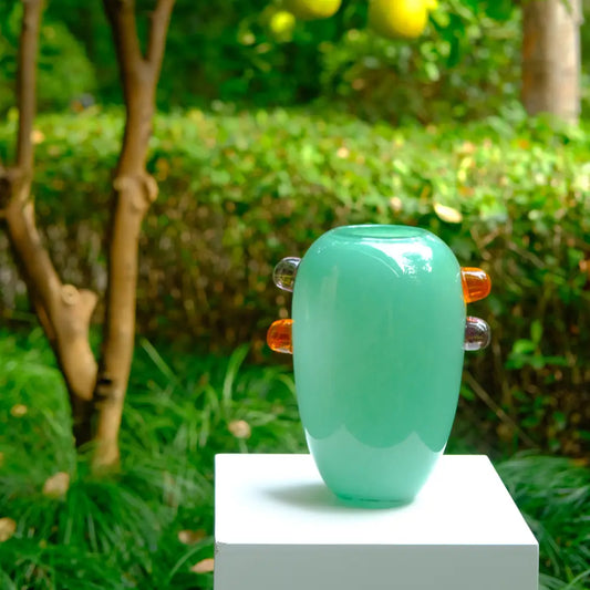 Grand vase en verre vert avec détails ambrés, design contemporain et élégant.