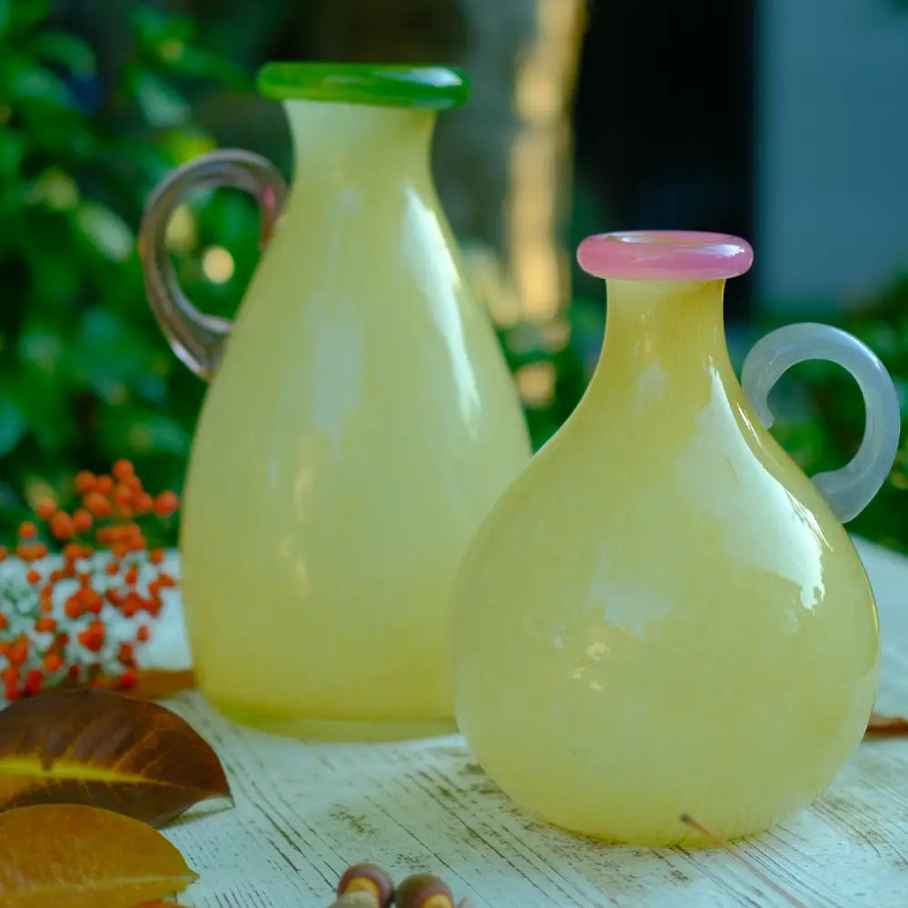 Petit vase en verre aux tons doux, anse rose texturée et col vert pour un style unique.