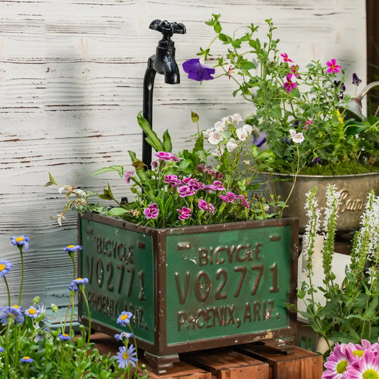 Pot de fleurs pour balcon avec des fleurs colorées et un robinet décoratif en métal.
