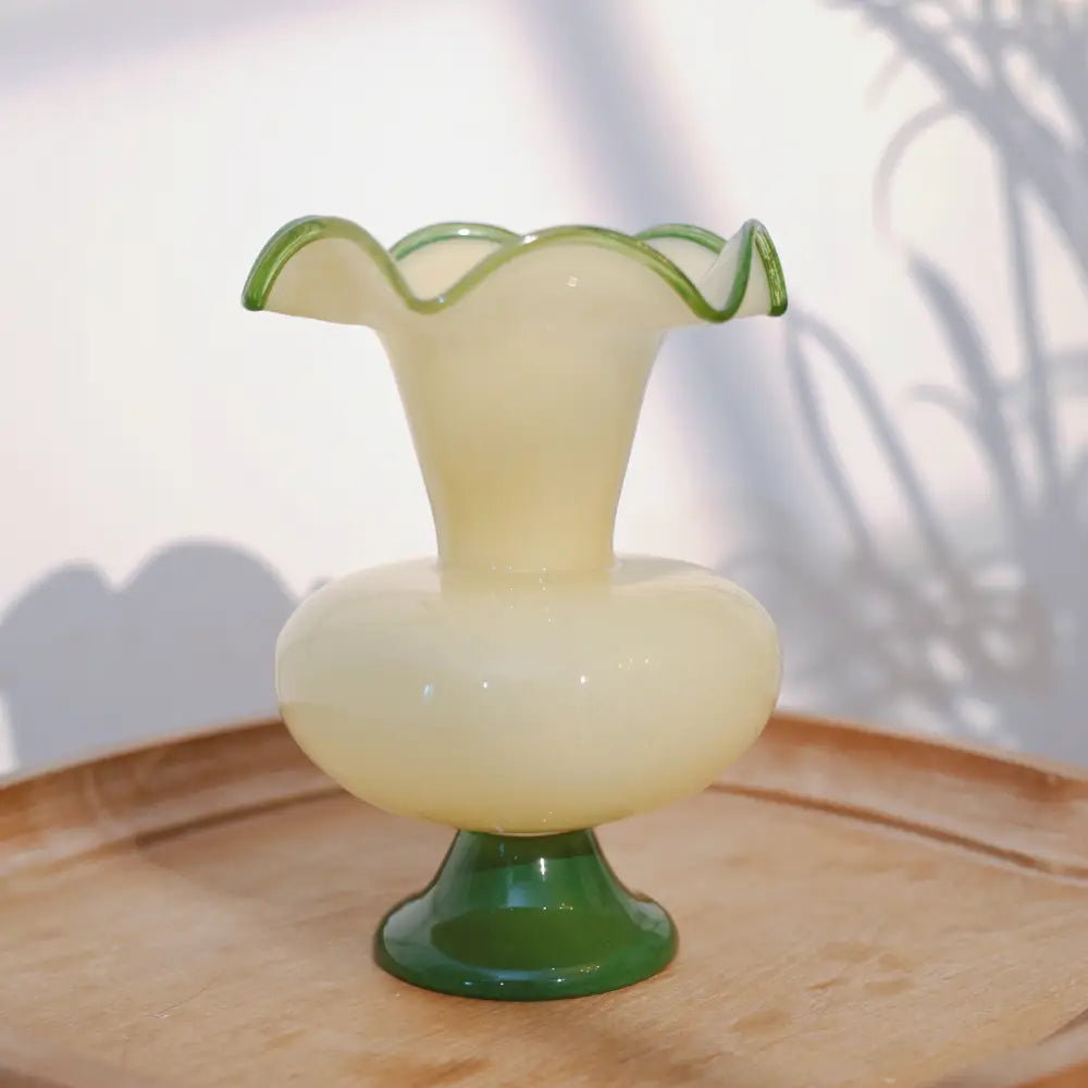 Vase en verre artisanal de couleur ivoire avec bordure verte, objet design pour salon ou table d’appoint.