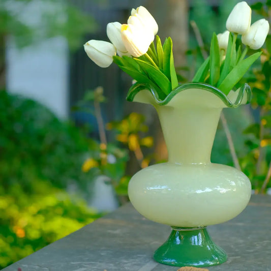 Vase en verre à pied crème avec bord ondulé vert, au design artisanal élégant.