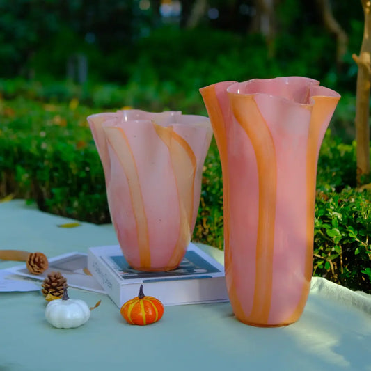 Vase design en verre soufflé aux tons rose et orange, avec bord ondulé en forme de pétales.