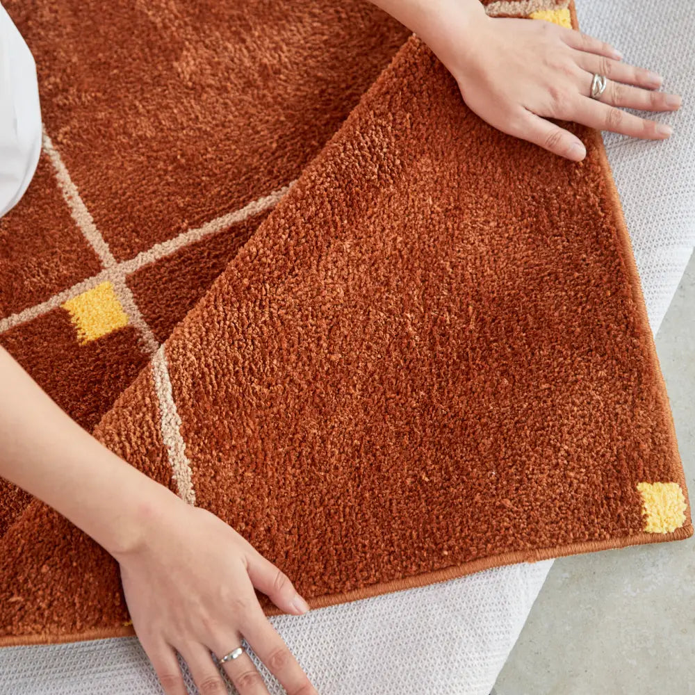 Tapis à carreaux marron au motif géométrique, ajoutant caractère et chaleur à un intérieur minimaliste.