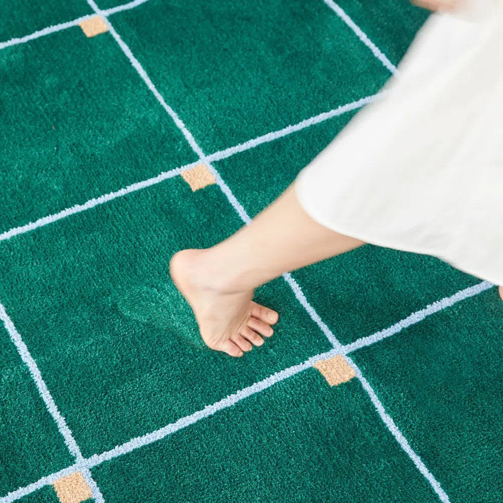 Tapis à carreaux vert posé près d’une chaise design, idéal pour créer une ambiance contemporaine et chaleureuse.