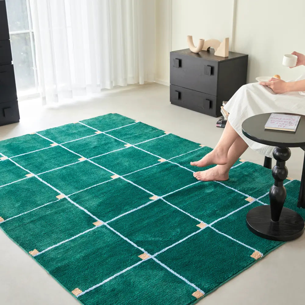 Décoration intérieure avec un tapis à carreaux vert, harmonisant mobilier noir et sol clair.
