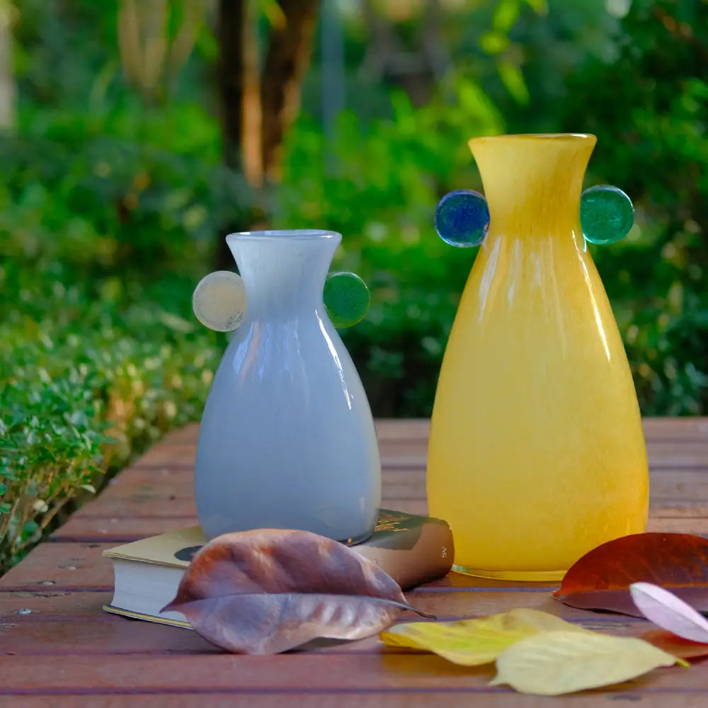 Décorer vase minimaliste en verre gris, orné de deux disques décoratifs latéraux.