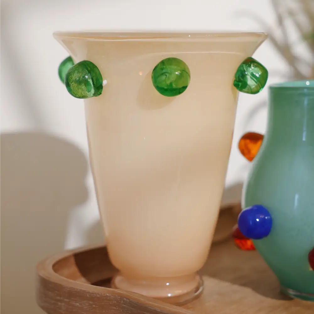 Grand vase en verre beige orné de pastilles vertes, au design moderne et élégant.