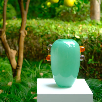 Grand vase en verre vert avec détails ambrés, design contemporain et élégant.