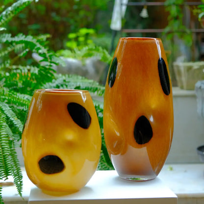 Grand vase décoratif en verre ambré avec motifs noirs, design moderne et élégant.