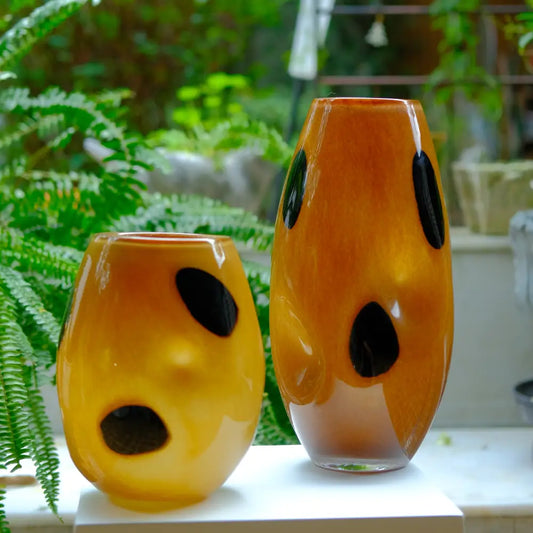 Grand vase décoratif en verre ambré avec motifs noirs, design moderne et élégant.