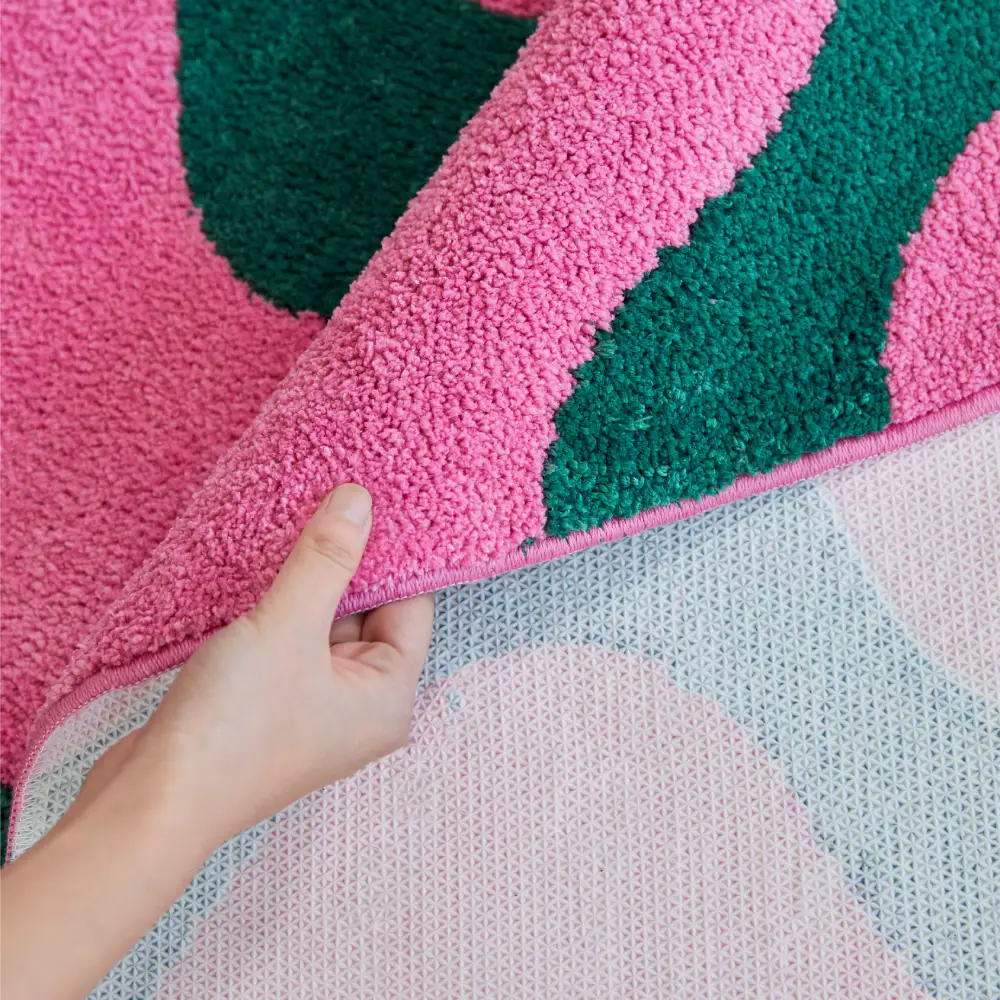 Tapis ondulé rose et vert près d’un grand canapé modulable, offrant une touche artistique et tendance à la pièce.