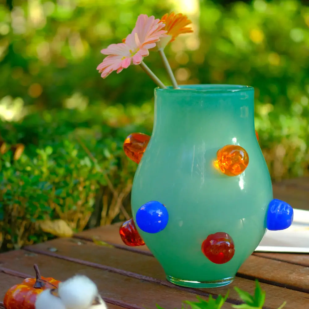 Petit vase en verre soufflé aux tons vert jade avec ornements colorés, idéal pour sublimer une table en bois.