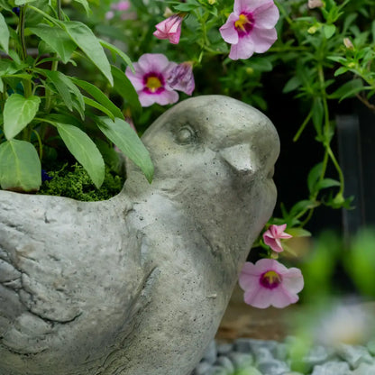 Pot de fleur intérieur – Jardinière oiseau en oxyde de magnésium avec fleurs roses et feuillage vert.