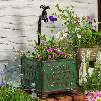 Pot de fleurs pour balcon avec des fleurs colorées et un robinet décoratif en métal.