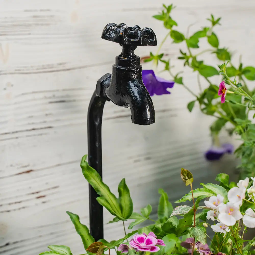 Pot de fleurs pour balcon – Robinet décoratif noir sur le balcon entouré de fleurs colorées.