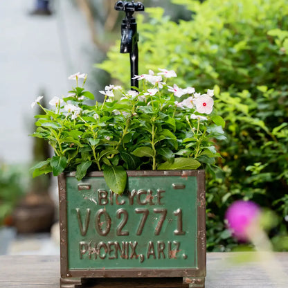 Pot de fleurs pour balcon avec des fleurs blanches et vertes dans un bac décoratif en métal patiné.