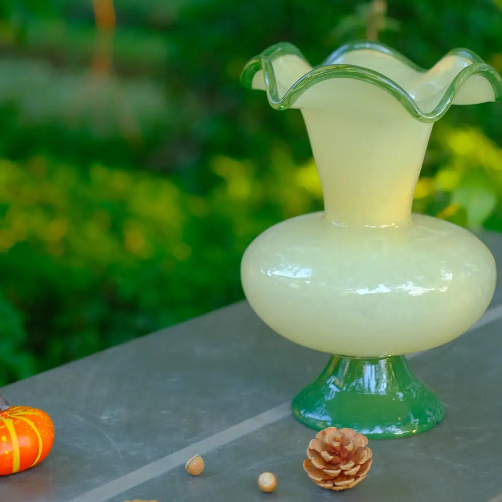 Vase en verre à pied soufflé à la bouche, silhouette sculpturale et base verte contrastée.
