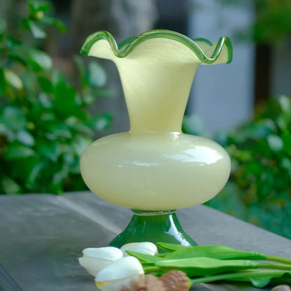 Vase en verre à pied pastel avec ouverture en forme de pétales, parfait pour une décoration raffinée.