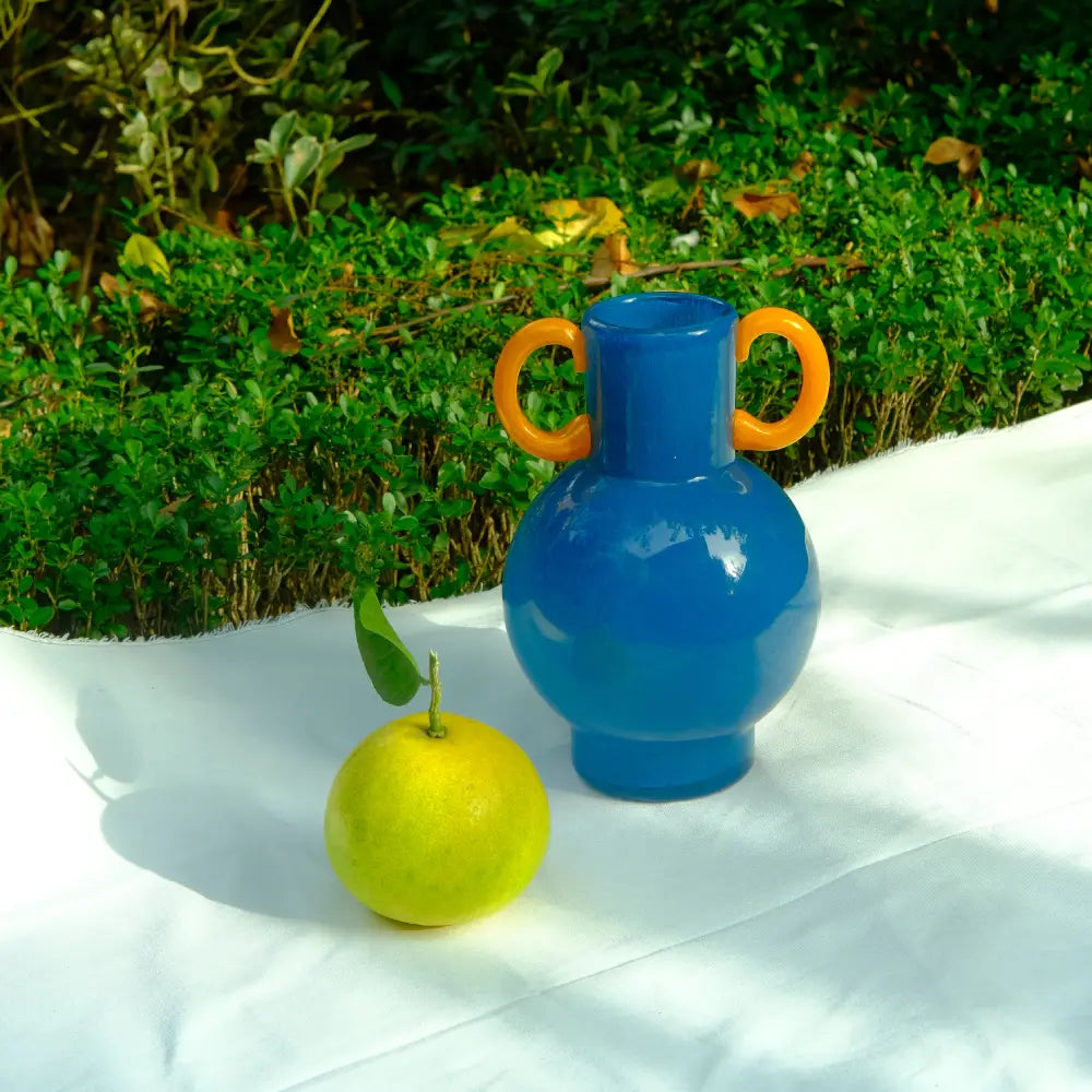 Vase déco amphore en verre bleu avec anses orange, design audacieux et contemporain.