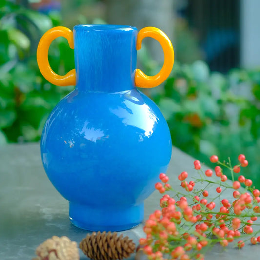 Vase déco amphore en verre soufflé bleu avec anses rondes jaunes au design contemporain.