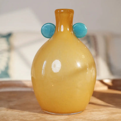 Vase jaune décoratif en verre artisanal, orné de détails bleus pour une touche contemporaine.