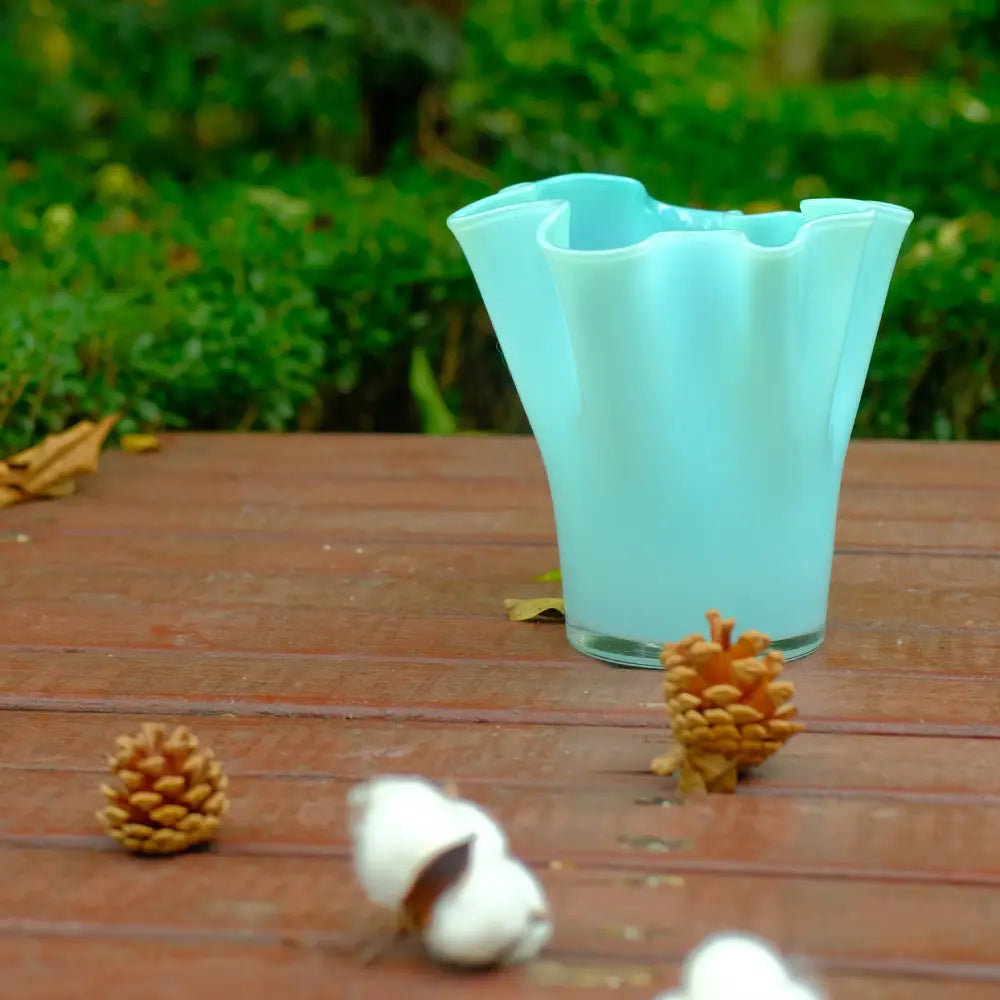Vase pour fleurs en verre bleu clair, au col ondulé et au design élégant.