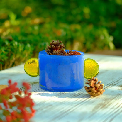 Vase bleu en verre opaque, orné de deux oreilles rondes jaunes pour une touche audacieuse.