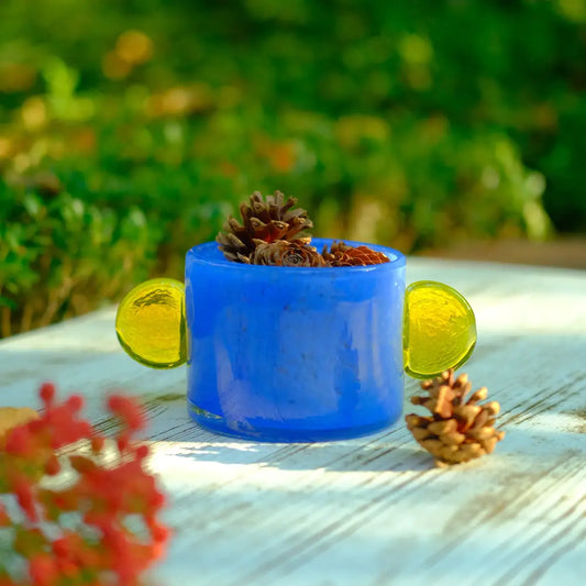 Vase bleu en verre opaque, orné de deux oreilles rondes jaunes pour une touche audacieuse.