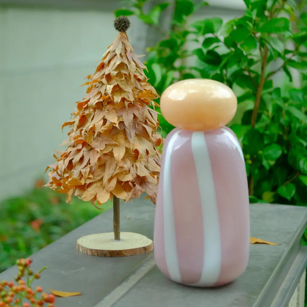 Vase rayé rose et blanc avec couvercle rouge, parfait pour une touche artistique et colorée.