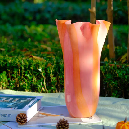 Vase design en verre artisanal aux nuances pastel, présenté en extérieur sur une table.