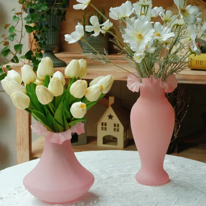 Vase rose mat en verre soufflé, forme évasée avec col ondulé. Idéal pour tulipes ou fleurs fraîches sur une table romantique.