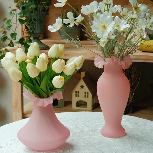Vase rose mat en verre soufflé, forme évasée avec col ondulé. Idéal pour tulipes ou fleurs fraîches sur une table romantique.