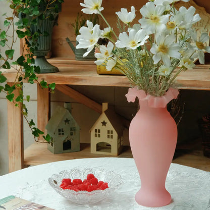 Vase rose en verre dépoli orné de fleurs blanches, accessoire déco doux et féminin pour intérieur lumineux.