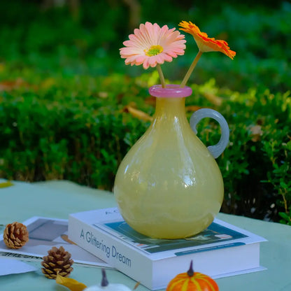 Vase soliflore décoratif de couleur miel avec poignée courbée et bord rose, parfait pour une fleur unique.
