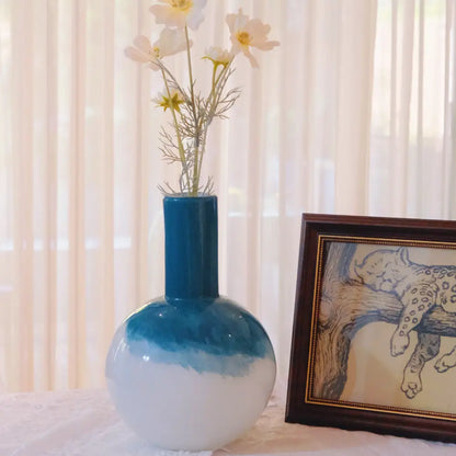 Vase bombé en céramique bleu et blanc, au col cylindrique élancé. Idéal pour une déco moderne et épurée sur table ou étagère